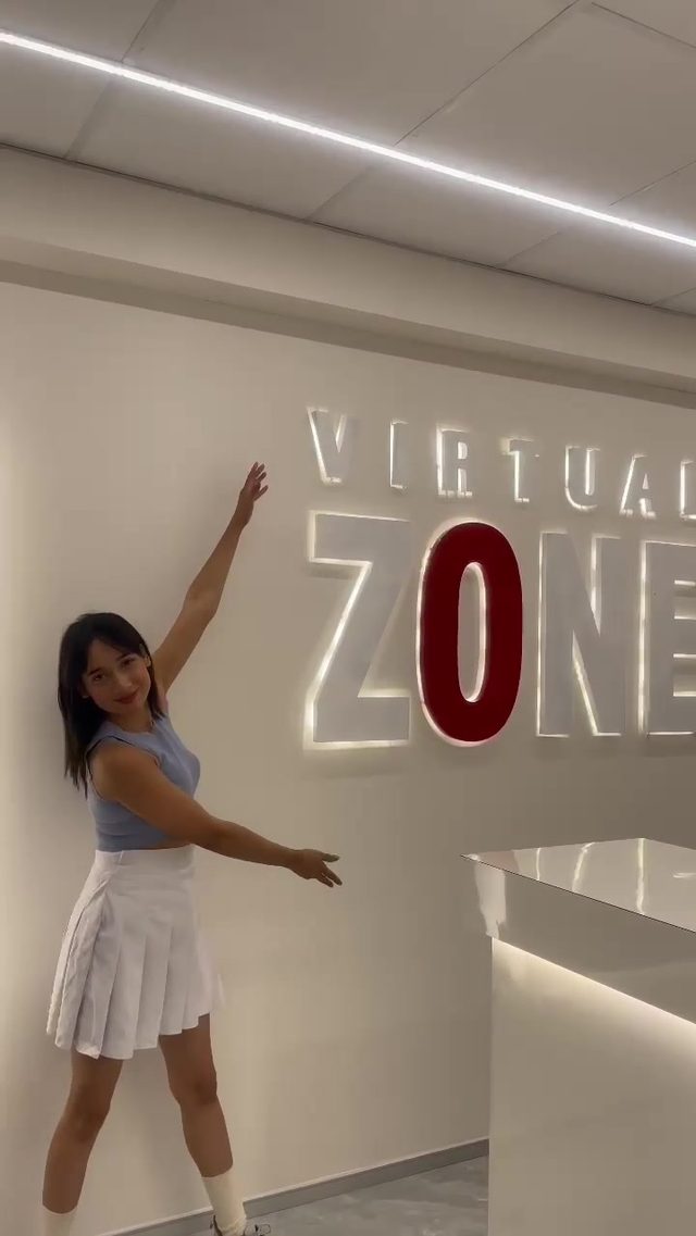 Visitor celebrating in front of the Virtual Zone wall logo after a session